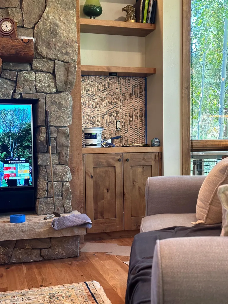 Penny backsplash in a wood cabinet alcove beside a stone fireplace