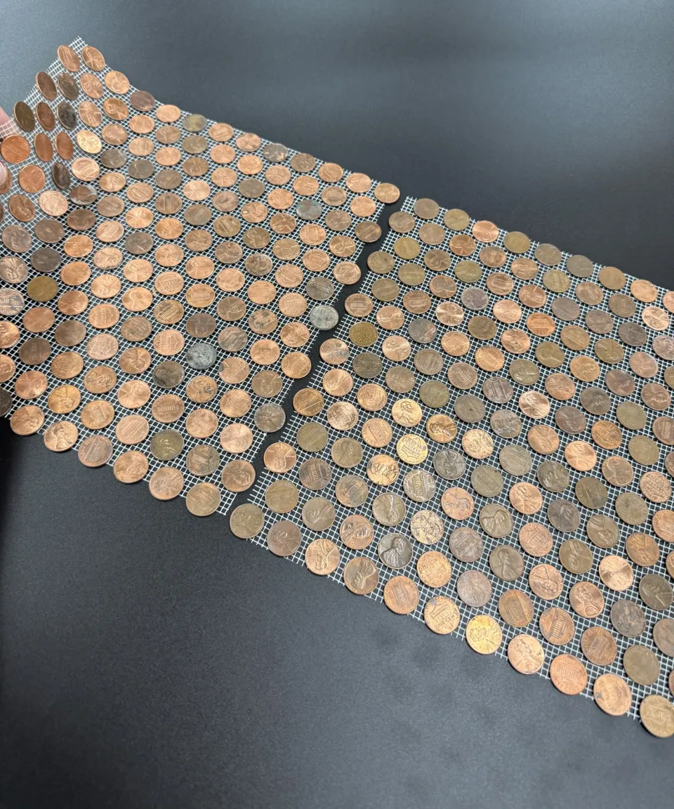 Two real interlocking penny tiles showing the connection between them